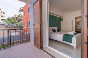 Un dormitorio con una cama, una pared verde y un baño con espejo.