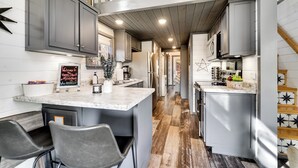 A modern kitchen with grey cabinets, a marble countertop, and a central island with bar stools. - Escape to your own Tiny Slice of Heaven in Franklin, N (Franklin)