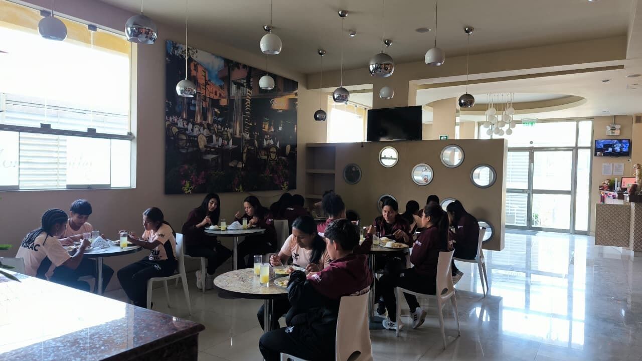 A dining area with round tables, chairs, and a large painting on the wall.