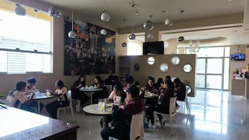 A dining area with round tables, chairs, and a large painting on the wall.