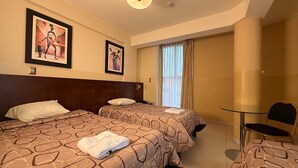 Ein Hotelzimmer mit zwei Betten, einem kleinen Tisch und einem Stuhl.