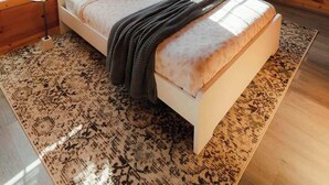 Un dormitorio de cabaña de madera con una cama, una silla, una mesita y un ventilador de techo.