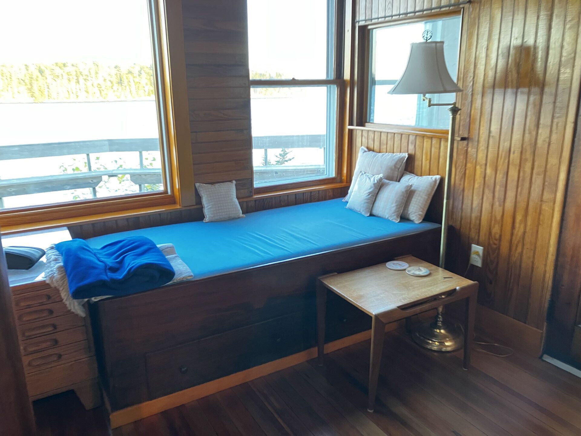 Una habitación acogedora de estilo cabaña con una cama empotrada, una mesita pequeña y una lámpara.