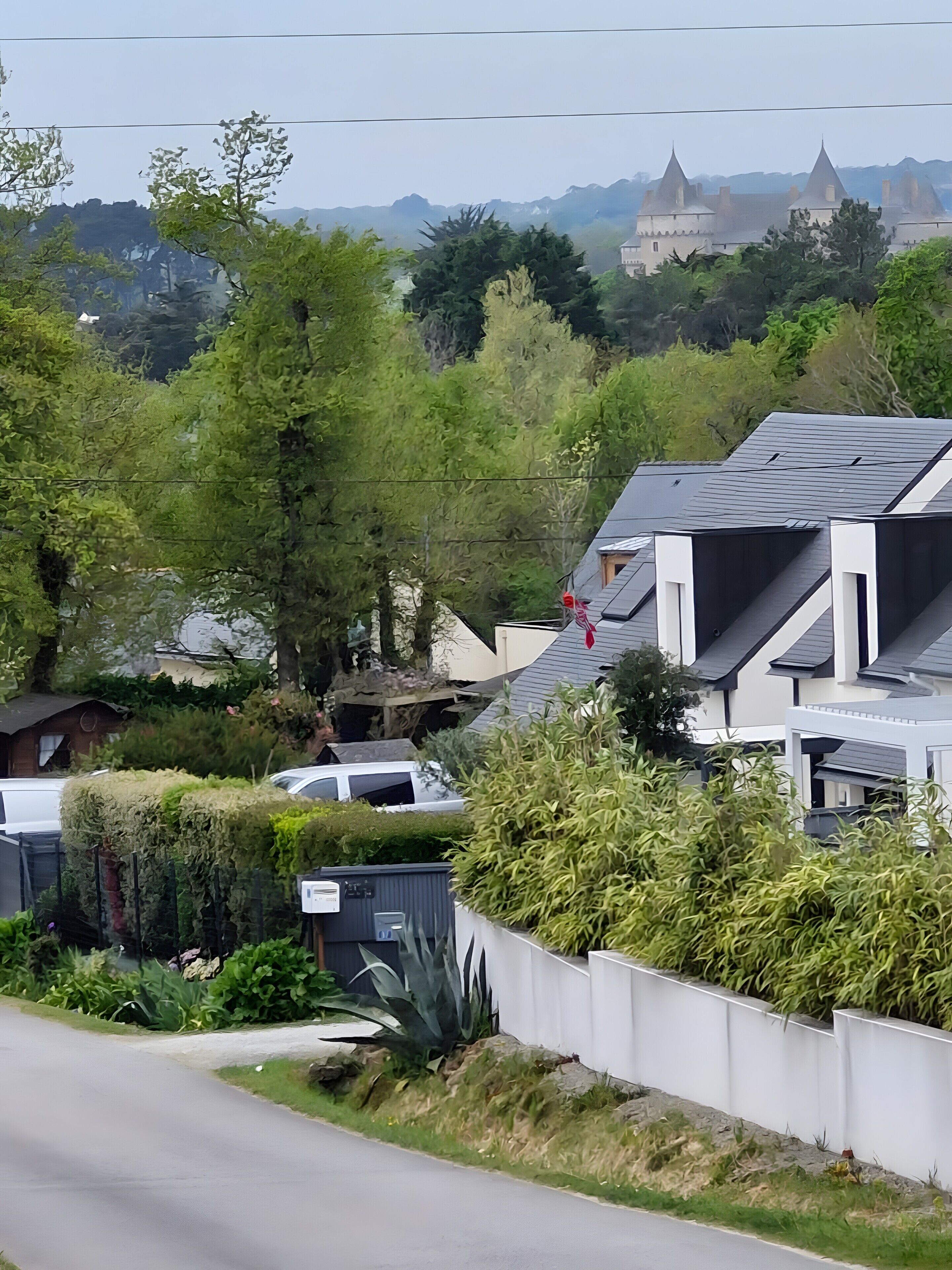 Zona residencial com casas modernas, uma estrada e um castelo ao longe.