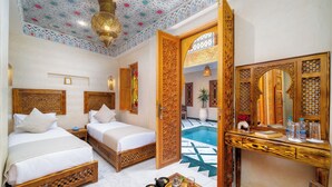 A hotel room with two beds, a wooden desk, a small pool, and a decorative ceiling. - Riad Nadalinn (Marrakech)