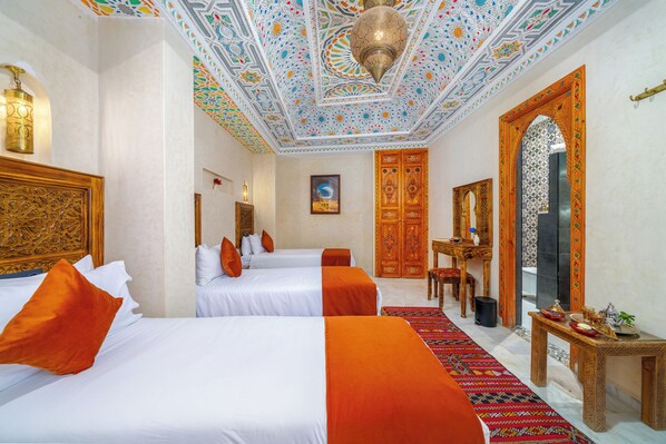 A hotel room with two beds, a desk, a chair, a patterned carpet, and a decorative ceiling. - Riad Nadalinn (Marrakech)