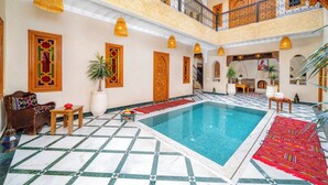 A multi-level indoor pool area with a tiled floor, a wooden bench, and a potted plant. - Riad Nadalinn (Marrakech)