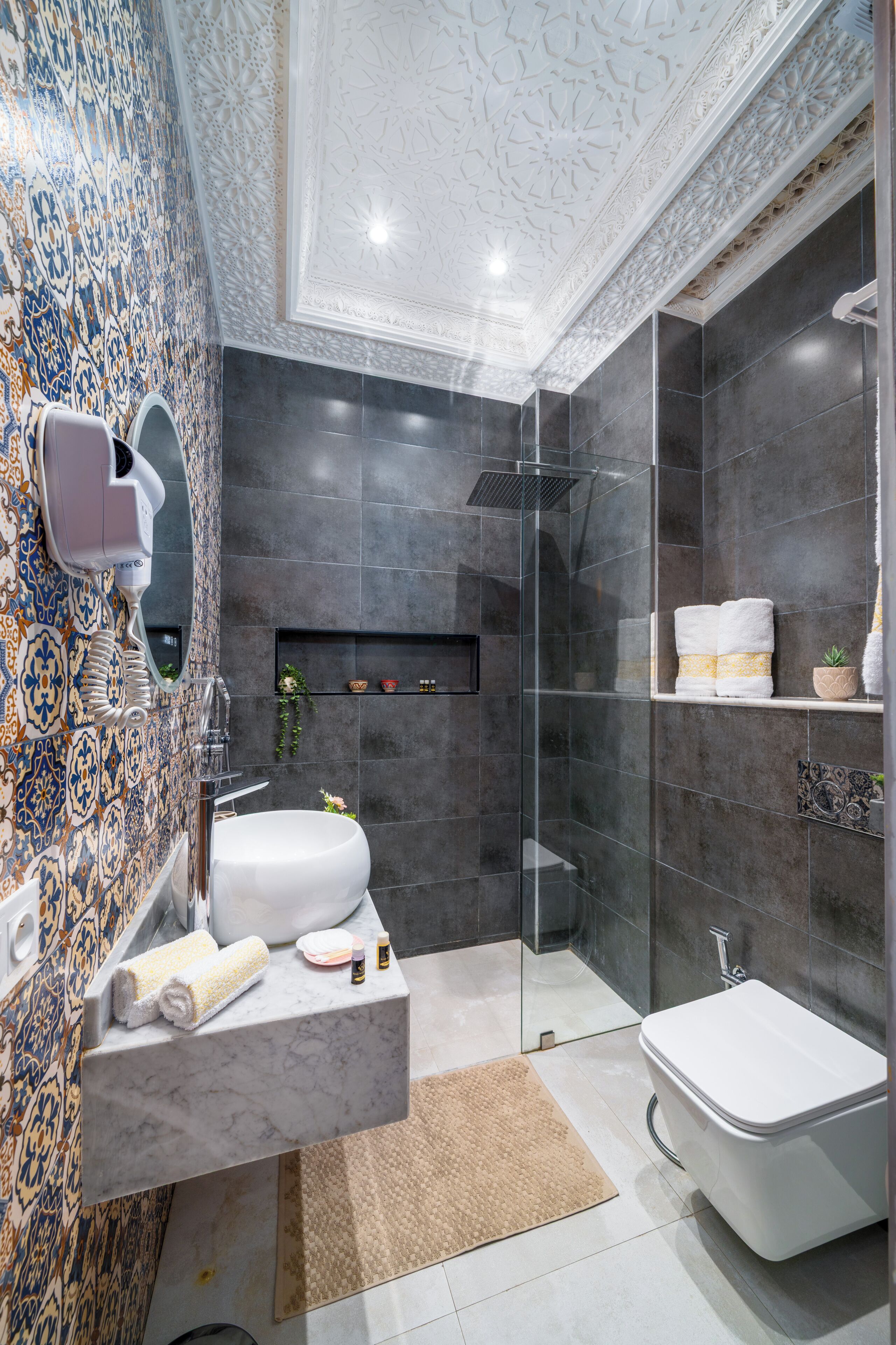 A modern bathroom with a marble sink, a glass-enclosed shower, and a white toilet.