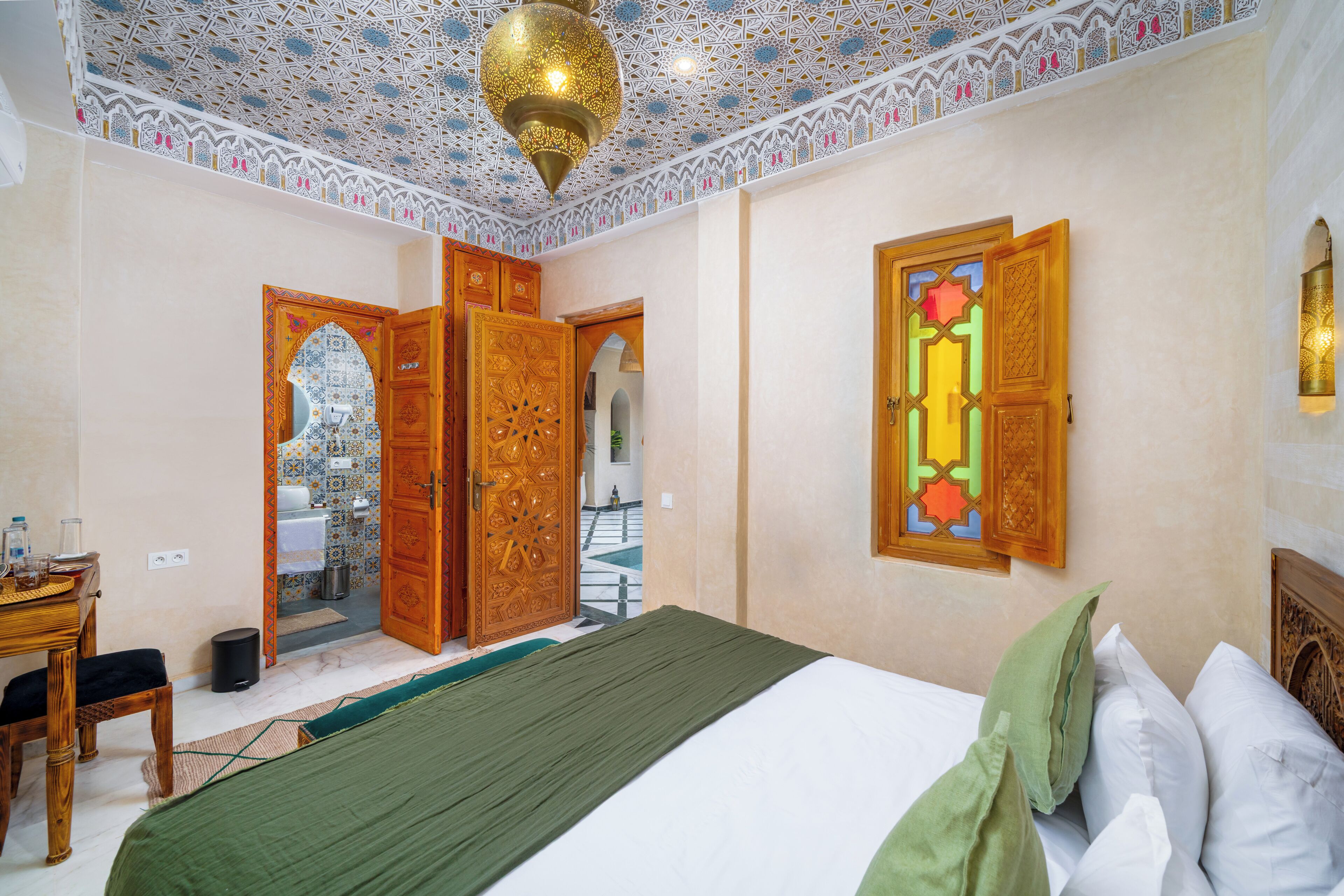 A room with a bed, a desk, and a bathroom visible through an open door.