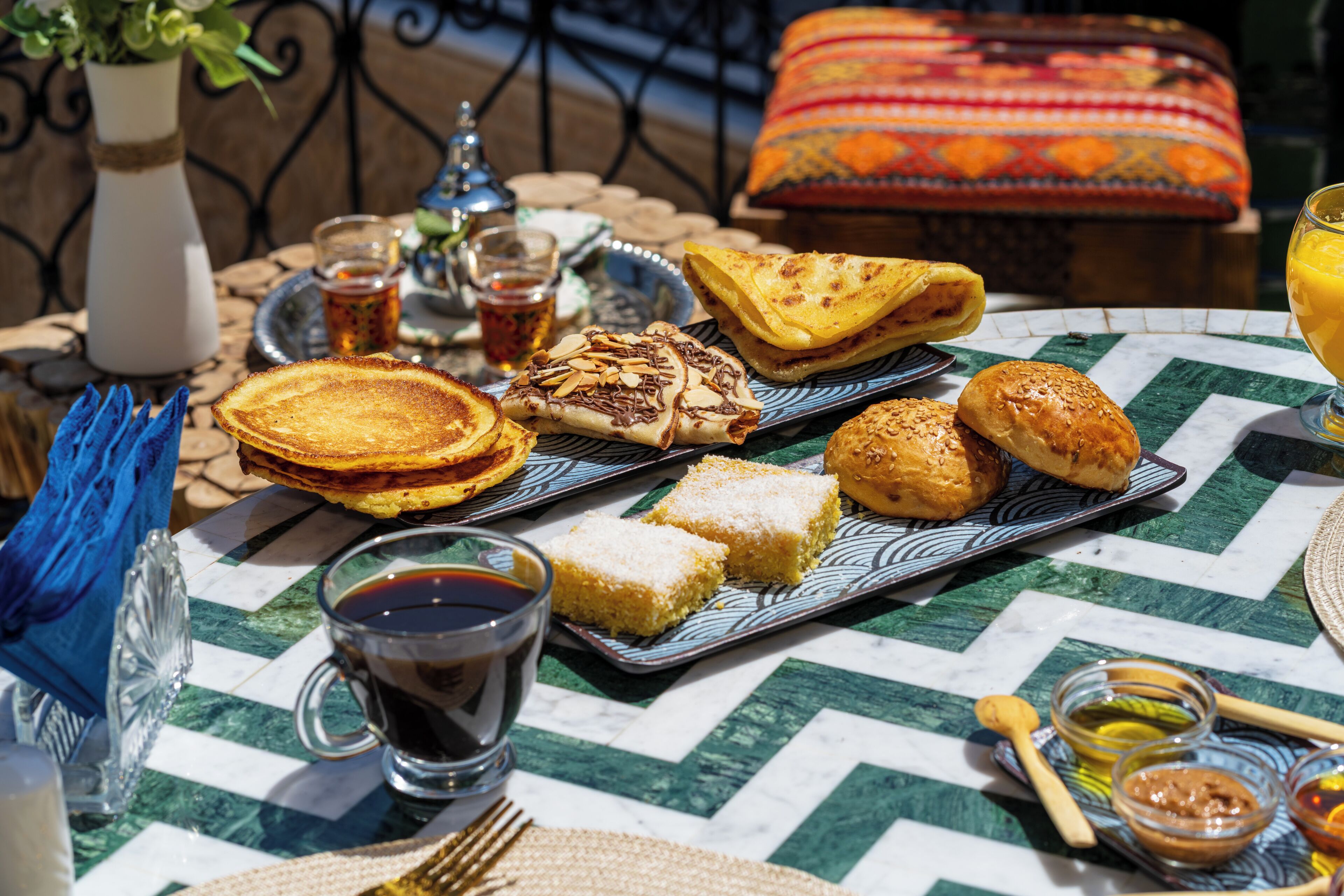 A table with various foods and drinks, including bread, pastries, and a cup of tea.