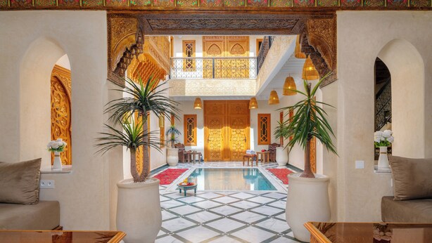 A spacious lobby with a central pool, ornate arches, and potted plants. - Riad Nadalinn (Marrakech)