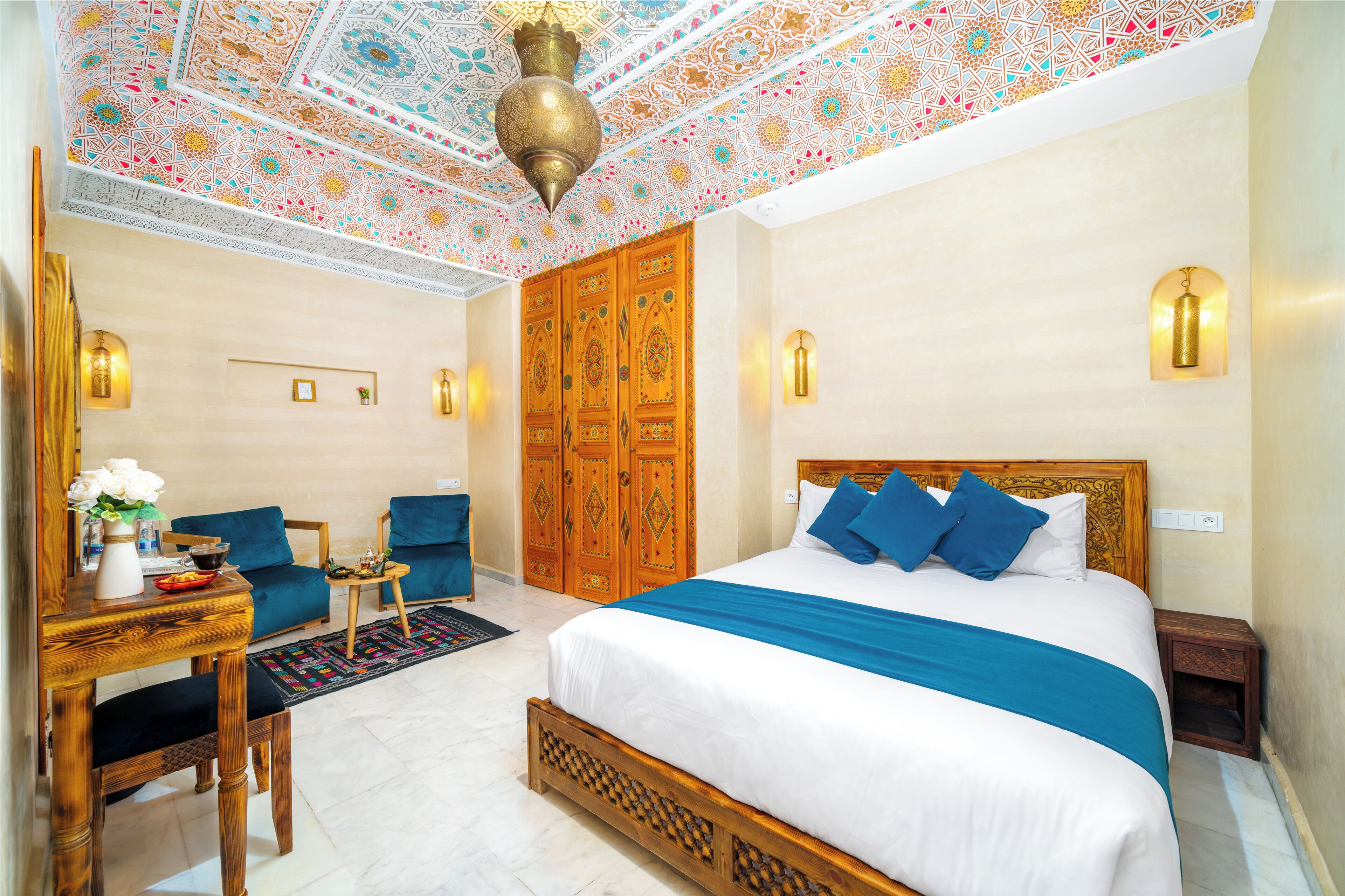 Una camera da letto con un letto grande, una scrivania con una sedia, un divano e un soffitto decorato.