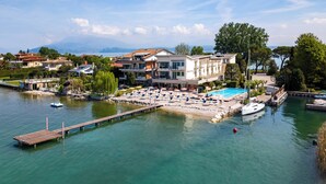 A waterfront property with a swimming pool, dock, and boats. - Hotel Tre Vele (Sirmione)