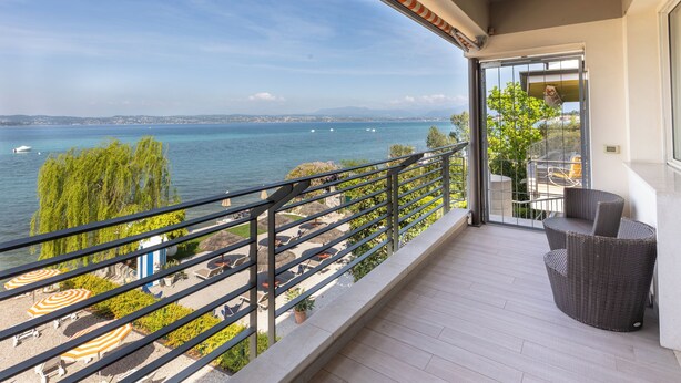 A balcony with a view of the sea, outdoor furniture, and a railing. - Hotel Tre Vele (Sirmione)