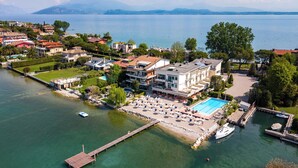 A waterfront property with a swimming pool, dock, and boats. - Hotel Tre Vele (Sirmione)