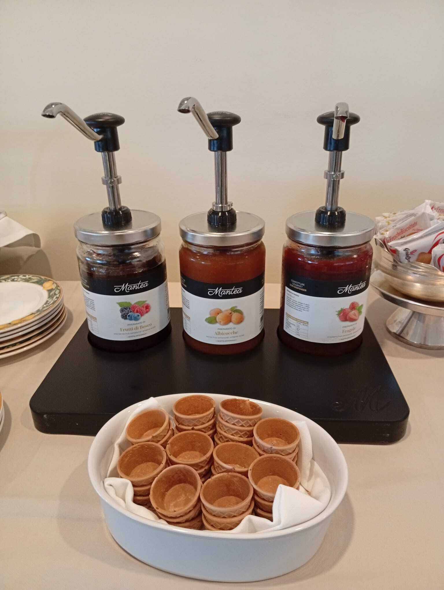 Tre distributori di condimenti con etichette, una ciotola di waffle e un vassoio di biscotti.
