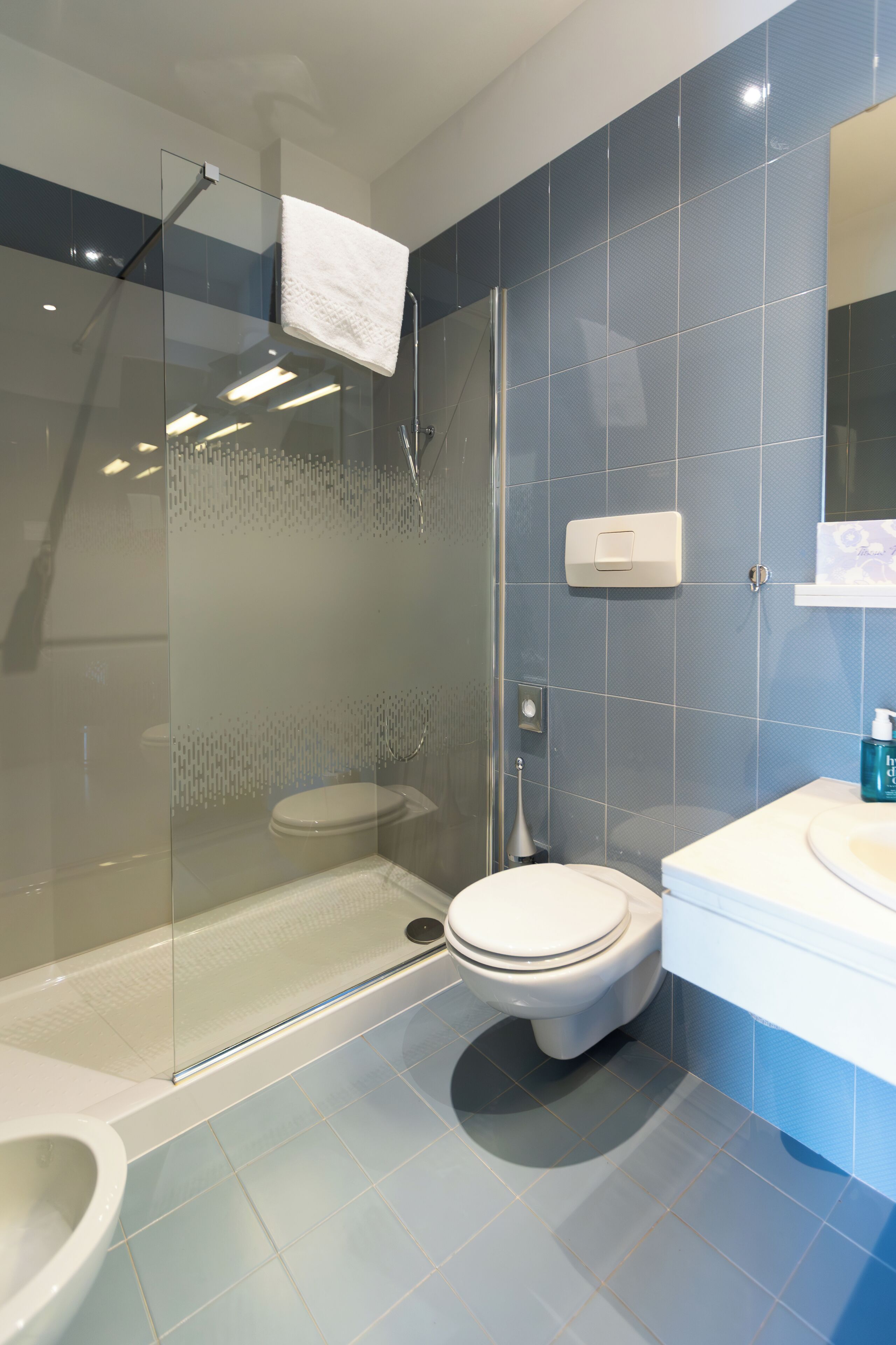 A modern bathroom with a glass-enclosed shower, a toilet, and a sink.