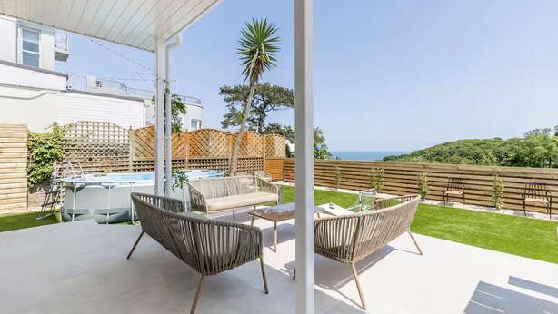 Un espace extérieur abrité comprenant une piscine, des chaises longues et une vue sur la mer.