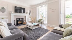 Un salon moderne doté d’une cheminée, d’un téléviseur à écran plat et d’un coin salon confortable.