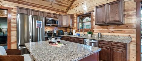 A modern kitchen with granite countertops, stainless steel appliances, and wooden cabinetry.