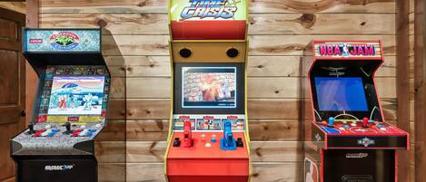 Three arcade machines: Time Crisis, Capcom, and NBA Jam, against a wooden wall.