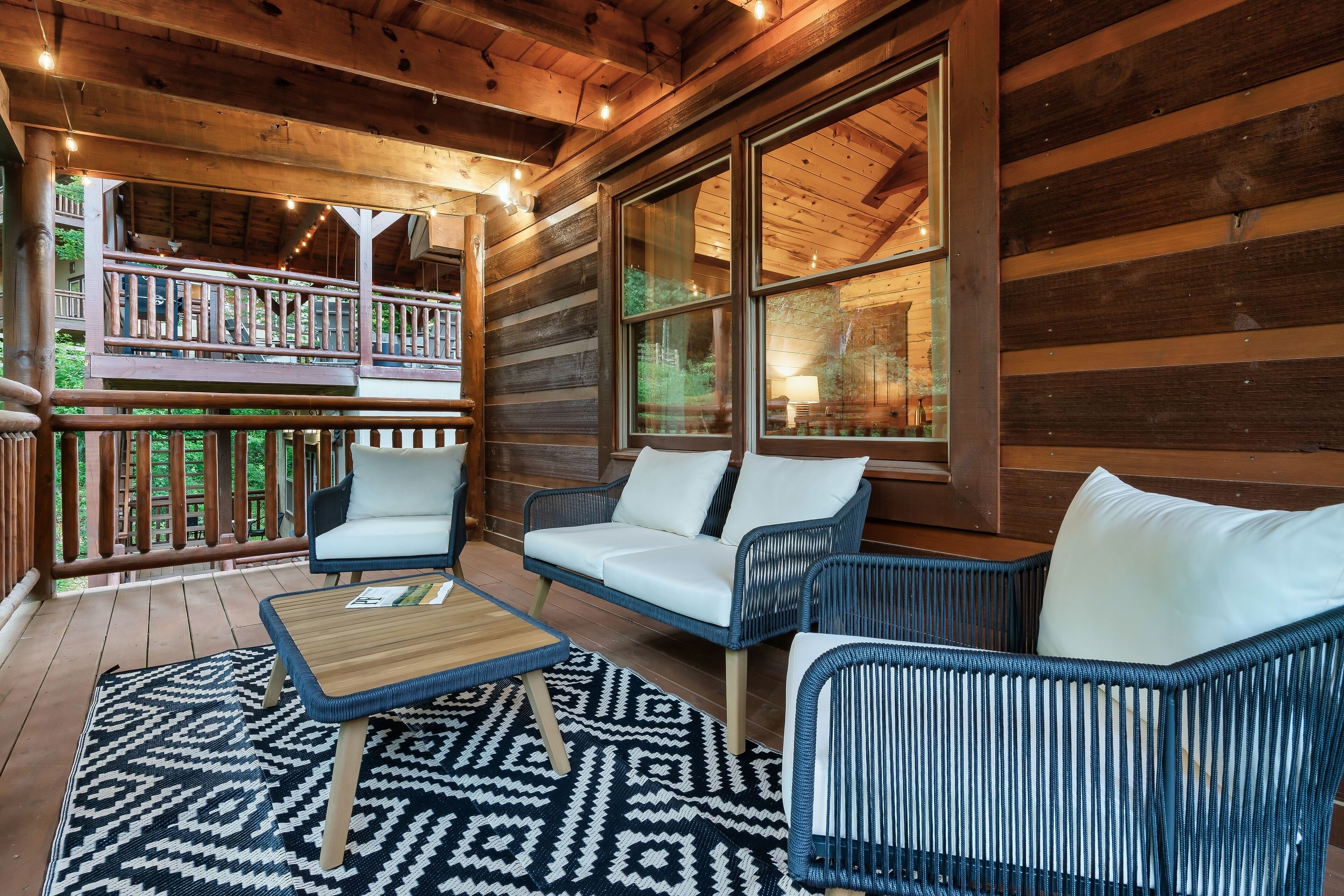 A wooden deck with wicker furniture and a patterned rug.
