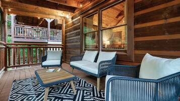 A wooden deck with wicker furniture and a patterned rug.