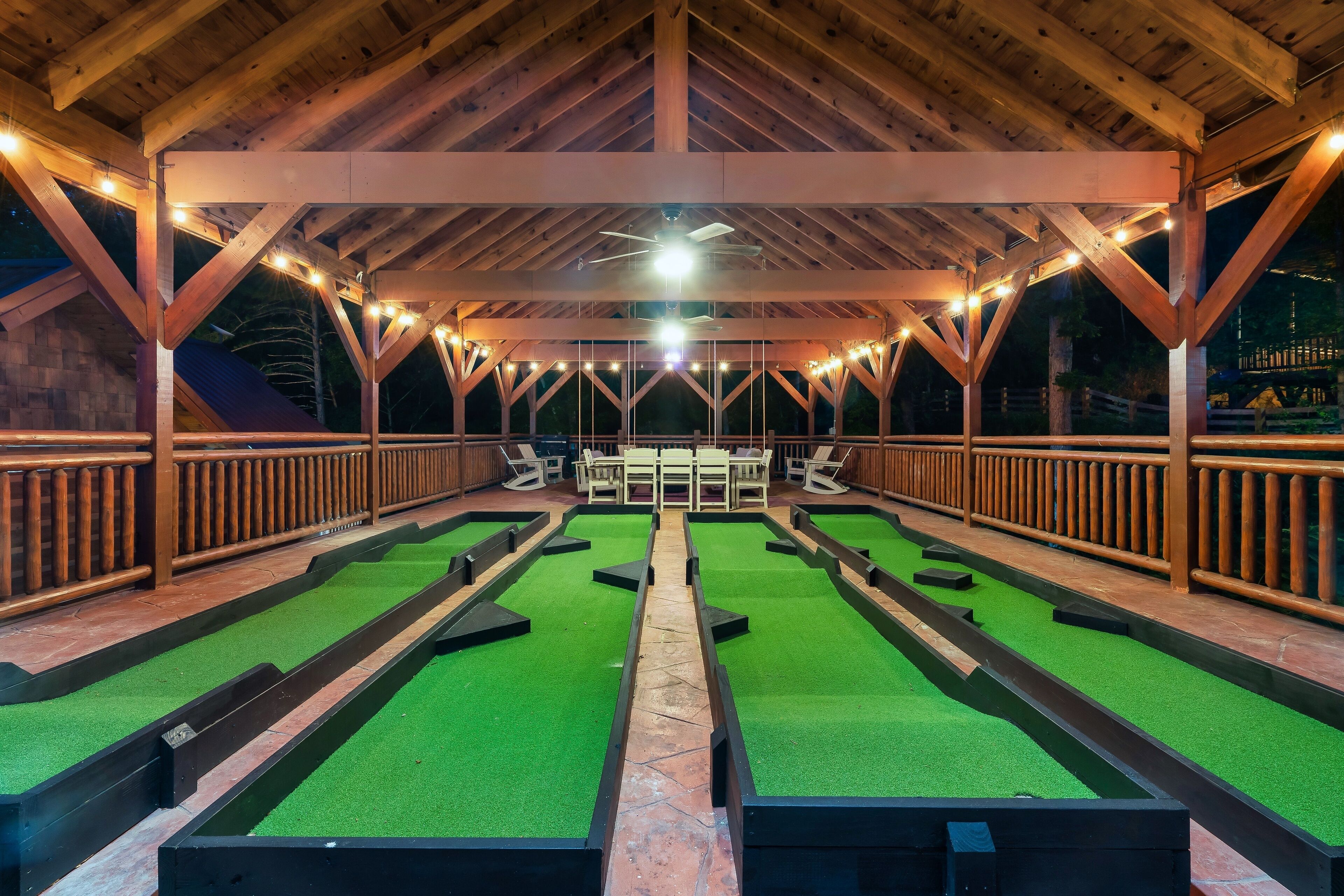 Une salle de billard dotée de plusieurs tables, de poutres en bois et de guirlandes lumineuses.