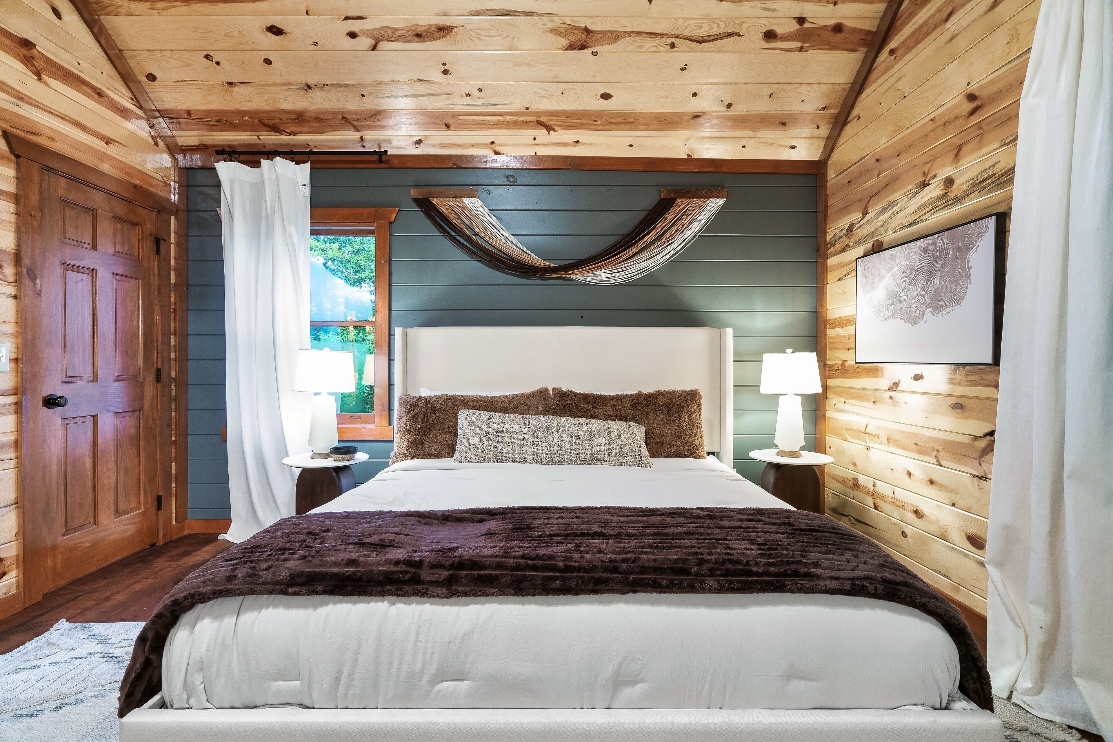 Ein Schlafzimmer mit Holzwänden, einem Bett, einer Hängematte und einem Bild an der Wand.