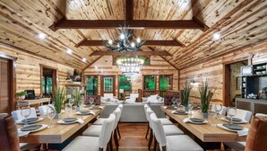 A log cabin-style dining area with a central seating arrangement, wooden beams, and a chandelier. - Big Chief Lodge (Sevierville)