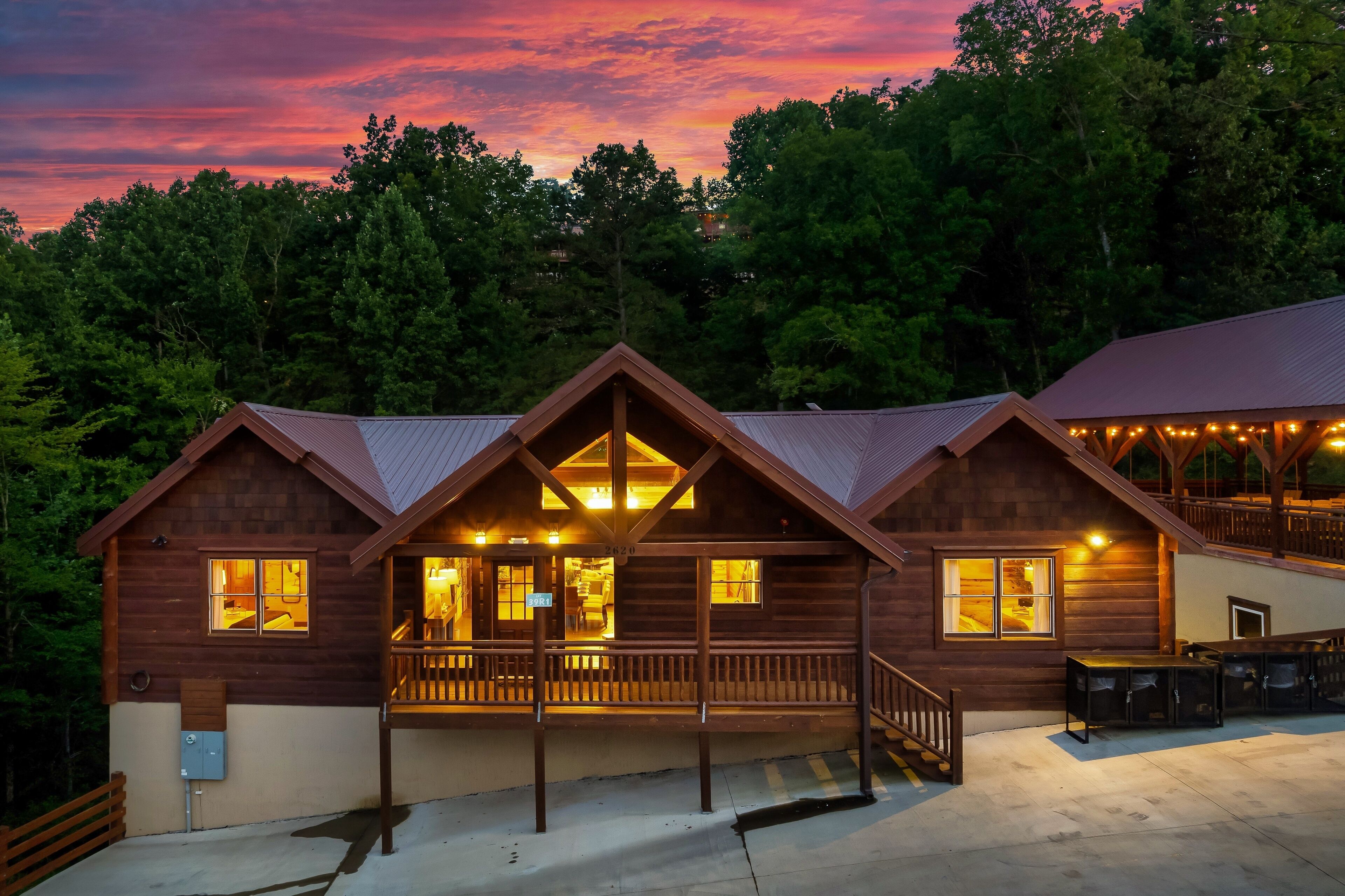 A wooden cabin with a porch, multiple windows, and a covered outdoor seating area.