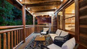 A wooden deck with outdoor furniture, a staircase, and a view of the interior. - Big Chief Lodge (Sevierville)