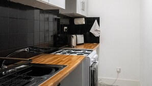 Una cucina moderna con mobili bianchi, uno schienale nero, un piano di lavoro in legno, un fornello a gas, un forno incassato e un forno a microonde.