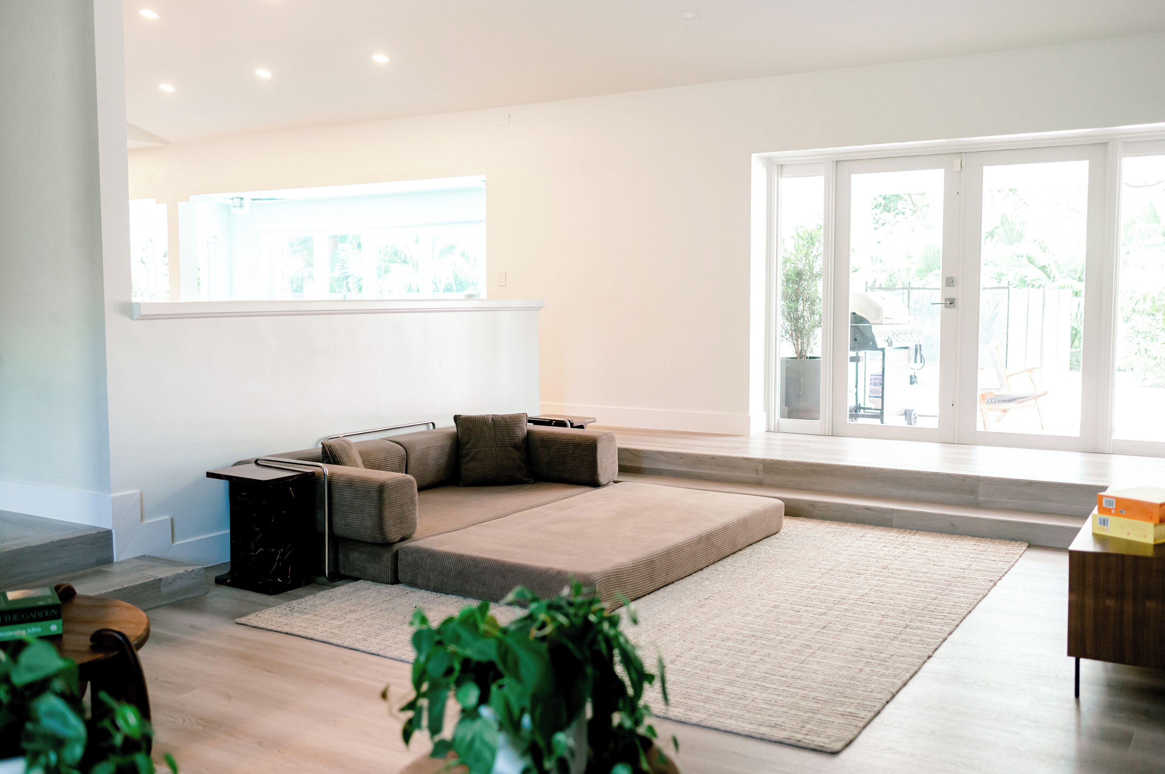 Uma sala de estar moderna com um sofá seccional, uma mesinha de centro, uma janela grande e vista para o exterior.
