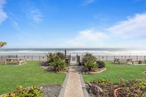 A pathway leading to a beachside patio area with picnic tables and a view of the ocean. - 🌊Oceanfront | Incredible Views | Perfect Couples Getaway | Oceanside 313🌊 (Daytona Beach)