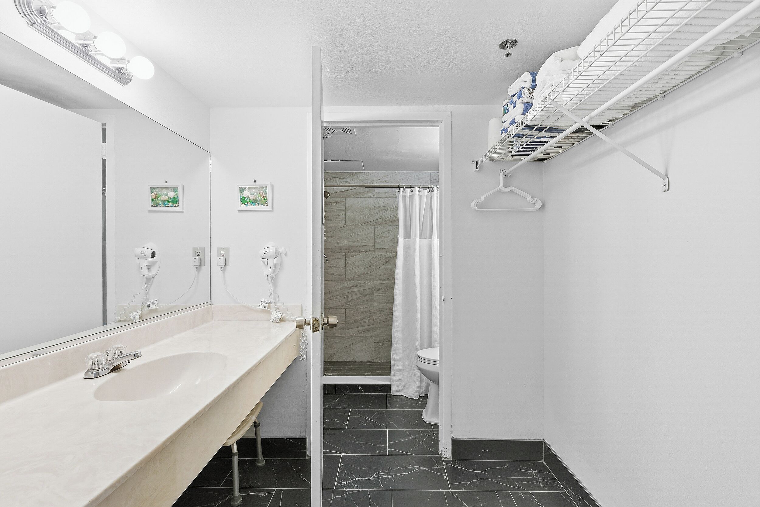 A modern bathroom with a large mirror, a sink, a toilet, and a shower area.