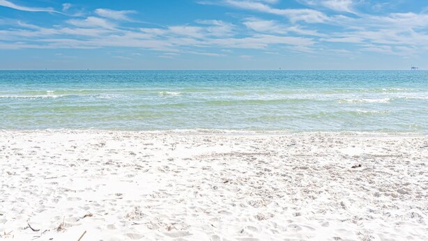 En strand med kristallklart blått vatten och en sandstrand.