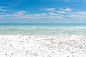 A beach with clear blue water and a sandy shore.