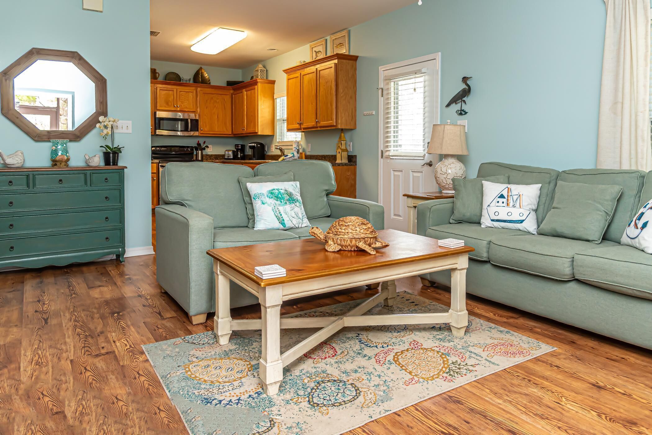 A cozy living room with a green sofa, a wooden coffee table, and a patterned rug.