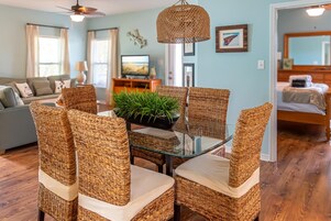 A living room with wicker furniture, a glass-top table, and a ceiling fan.
