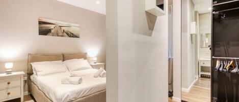 A modern bedroom with a large bed, bedside tables, a mirror, and a wardrobe.