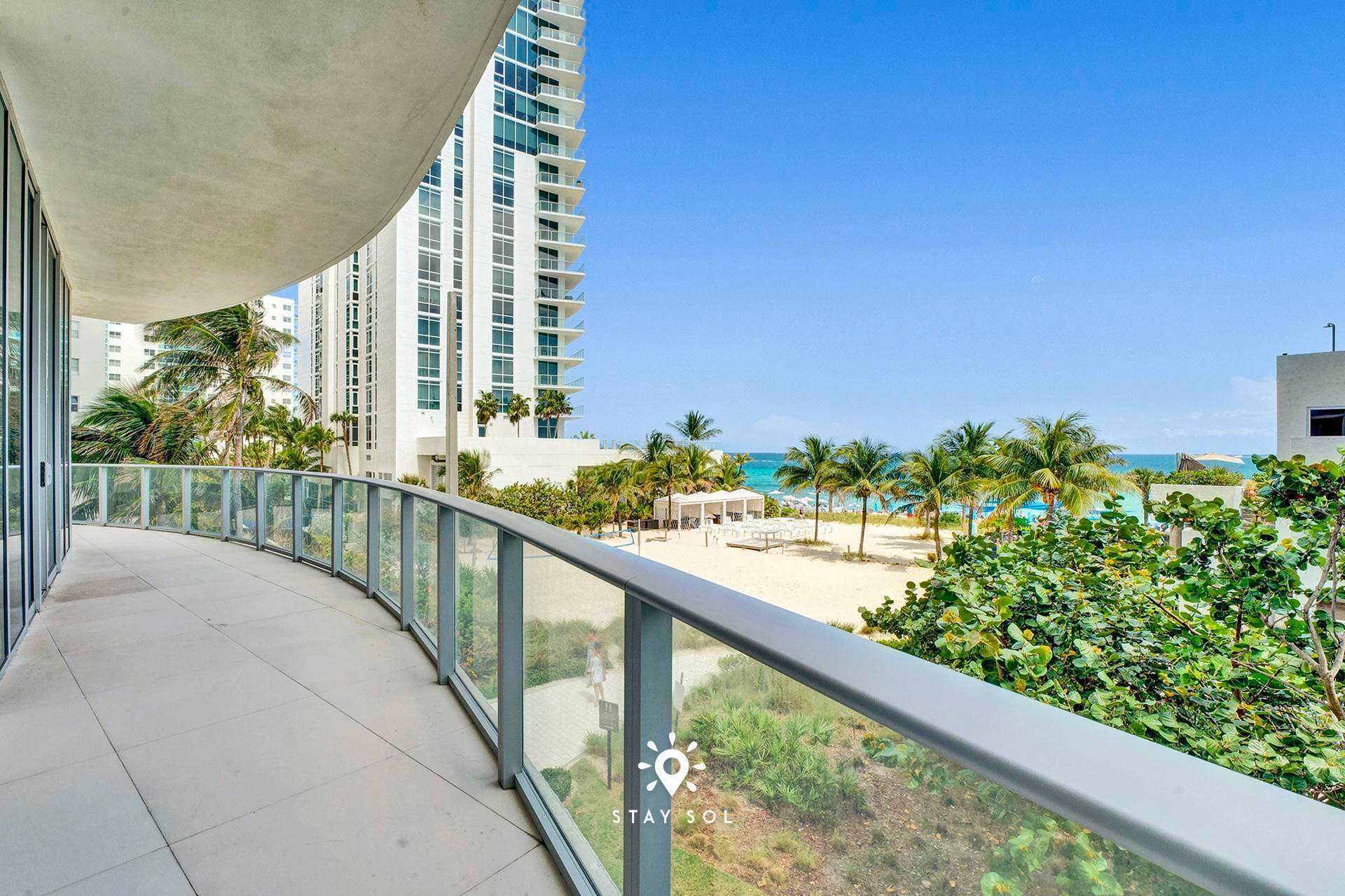 Een balkon met uitzicht op een strand en palmbomen.