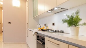 A modern kitchen with white cabinets, a stainless steel sink, and a potted plant. - Elegant Sea View Apartment with Panoramic Patio (Grottammare)