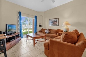 A living room with a sofa, coffee table, TV, and a lamp. - Headline (Davenport)