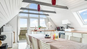 Un appartement moderne de style « loft », doté d’un espace repas, d’une cuisine et de grandes fenêtres.