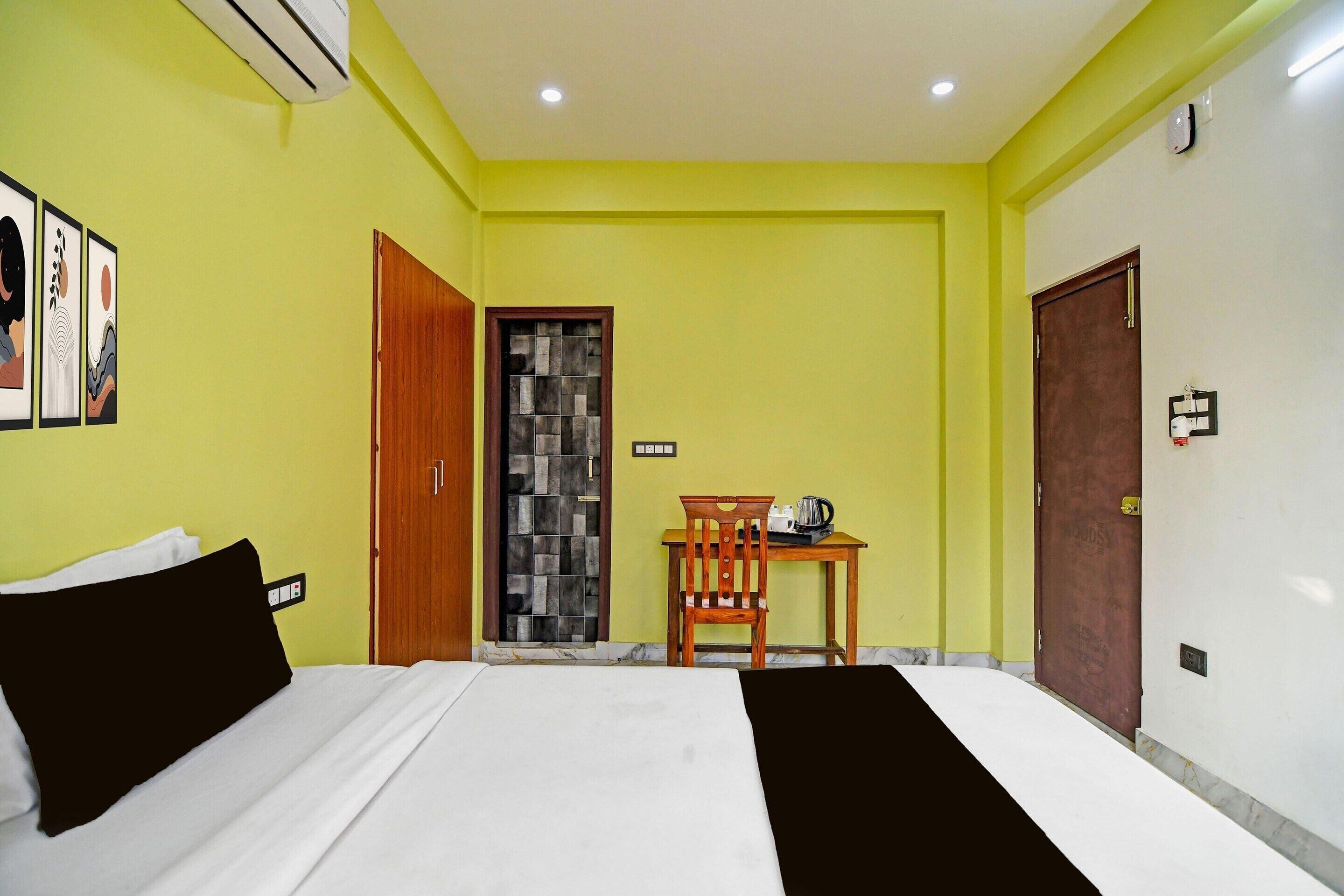 A hotel room with a bed, a desk, a chair, and a door.