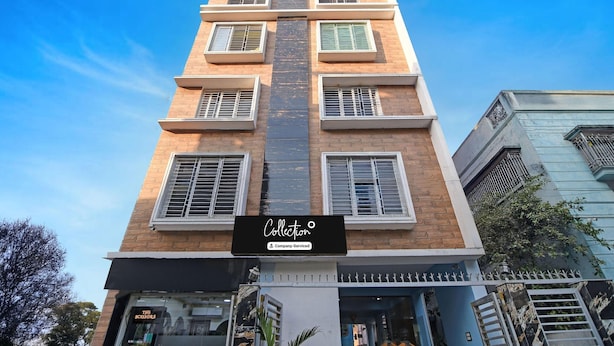 Un edificio de varios pisos con un cartel negro llamativo que dice 'Collection' y un cartel más pequeño debajo que indica 'Servicio de la empresa'.