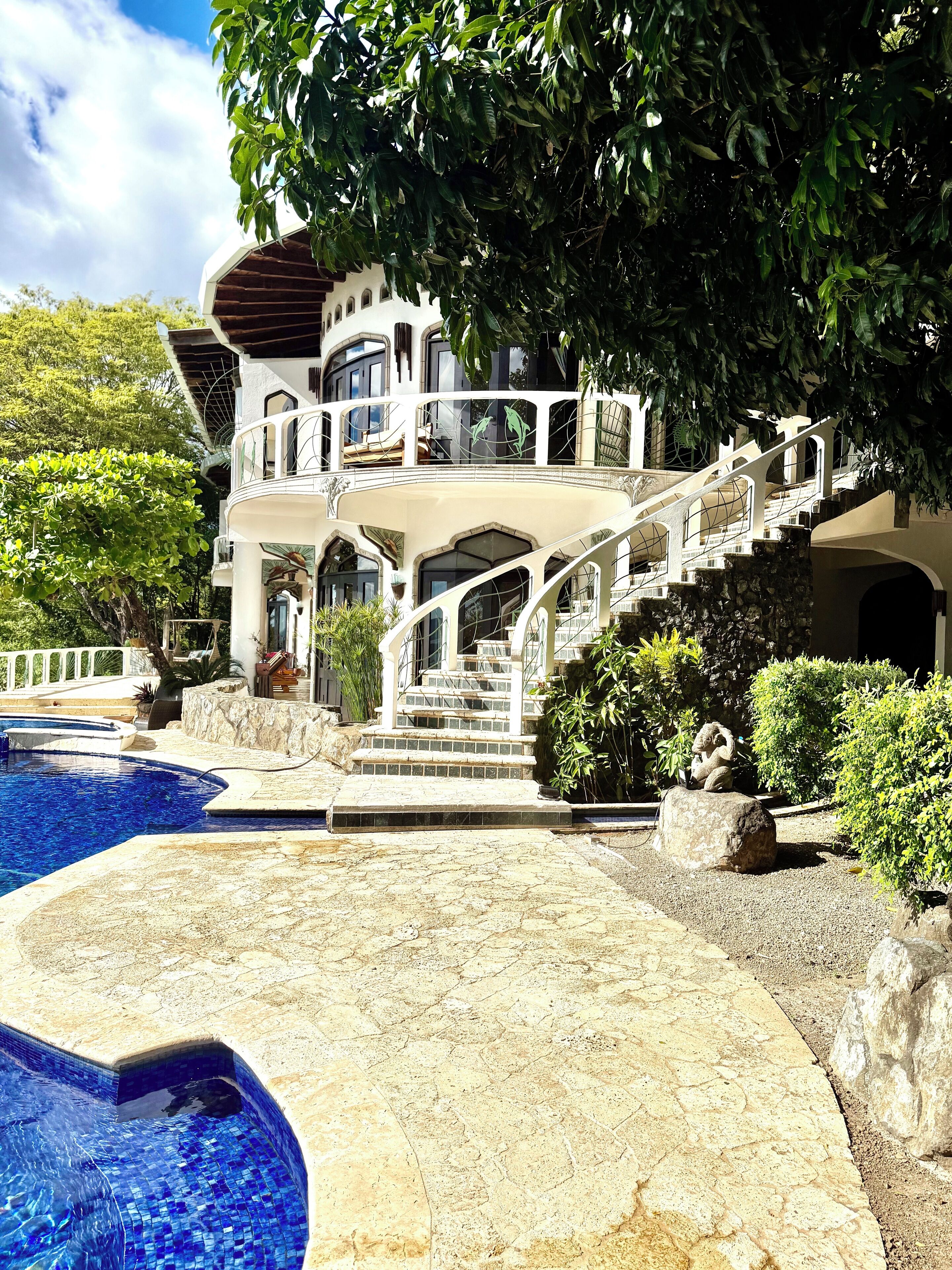 A luxurious house with a large swimming pool, a multi-level outdoor staircase, and a well-maintained garden.