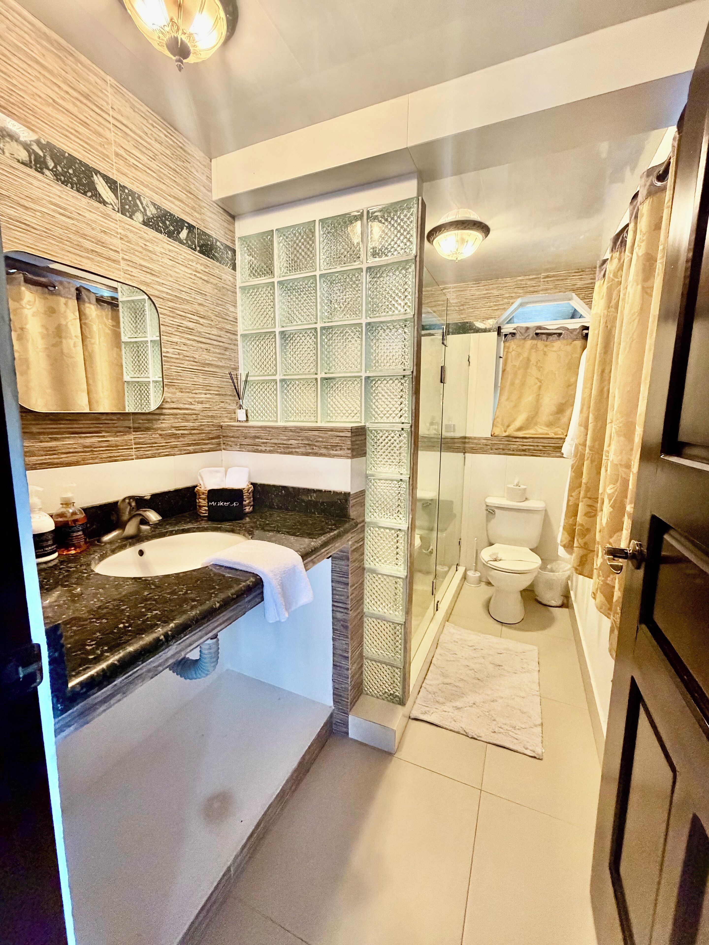 Une salle de bain avec un lavabo en marbre, une cabine de douche en verre et des toilettes.