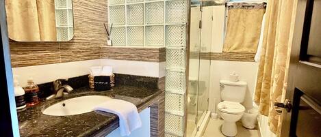Une salle de bain avec un lavabo en marbre, une cabine de douche en verre et des toilettes.